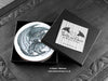 Set of four of my dragon coasters featuring my original pen and ink dragon illustrations, front view in an open black gift box with card. Made in the UK. Design and illustration © Nicola L Robinson | Teeth and Claws.