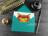 Persian cat greeting card, shown lying flat, with my original pen and ink illustration of a Persian cat, inside an open teal envelope. With vintage Victorian pen and writing desk accessories. Design and illustration © Nicola L Robinson | Teeth and Claws