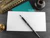 Persian cat greeting card, shown open and flat with blank inside, on a teal envelope, alongside vintage Victorian pen and writing desk accessories. Design and illustration © Nicola L Robinson | Teeth and Claws