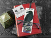 Raven bookmark featuring my original pen and ink illustration, front view of the bookmark resting on books with one of my branded cards. Made in the UK. Design and illustration © Nicola L Robinson | Teeth and Claws.