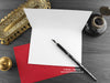 Raven and Rose love card, shown open and flat with blank inside, on a red envelope, alongside vintage Victorian pen and writing desk accessories. Design and illustration © Nicola L Robinson | Teeth and Claws