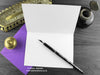 Raven birthday card, shown open and flat with blank inside, on a purple envelope, alongside vintage Victorian pen and writing desk accessories. Design and illustration © Nicola L Robinson | Teeth and Claws