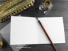 Red fire dragon greeting card, shown open and flat with blank inside, on a grey envelope, alongside vintage Victorian pen and writing desk accessories. Design and illustration © Nicola L Robinson | Teeth and Claws