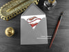 Red fire dragon greeting card, shown lying flat, with my original pen and ink illustration of a red dragon, inside an open grey envelope. With vintage Victorian pen and writing desk accessories. Design and illustration © Nicola L Robinson | Teeth and Claws