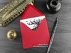 Gothic Reindeer Christmas card, shown lying flat, with my original pen and ink illustration of a Reindeer, inside an open red envelope. With vintage Victorian pen and writing desk accessories. Design and illustration © Nicola L Robinson | Teeth and Claws