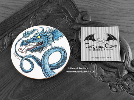 Blue Dragon Coaster featuring my original pen and ink illustration of a blue dragon, front view alongside one of my branded cards. Made in the UK. Design and illustration © Nicola L Robinson | Teeth and Claws.