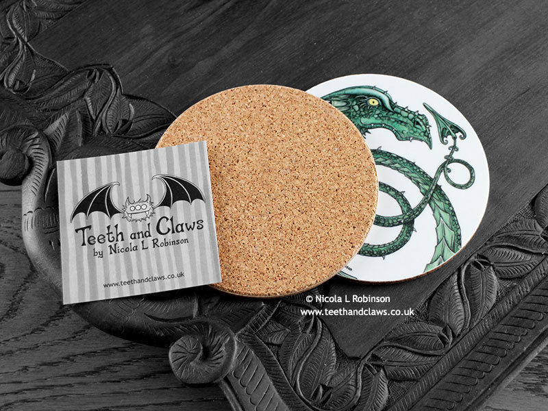 Green Dragon Coaster featuring my original pen and ink illustration of a green dragon, back view showing the cork backing, alongside one of my branded cards. Made in the UK. Design and illustration © Nicola L Robinson | Teeth and Claws.