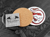 Red Dragon Coaster featuring my original pen and ink illustration of a red dragon, back view showing the cork backing, alongside one of my branded cards. Made in the UK. Design and illustration © Nicola L Robinson | Teeth and Claws.