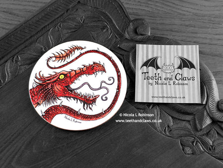 Red Dragon Coaster featuring my original pen and ink illustration of a red dragon, front view alongside one of my branded cards. Made in the UK. Design and illustration © Nicola L Robinson | Teeth and Claws.