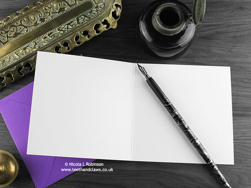 Gothic Spider Greeting card, shown open and flat with blank inside, on a purple envelope, alongside vintage Victorian pen and writing desk accessories. Design and illustration © Nicola L Robinson | Teeth and Claws