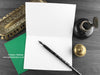 Spinosaurus greeting card, shown open and flat with blank inside, on a green envelope, alongside vintage Victorian pen and writing desk accessories. Design and illustration © Nicola L Robinson | Teeth and Claws
