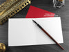 Cat Christmas card, shown open and flat with blank inside, on a red envelope, alongside vintage Victorian pen and writing desk accessories. Design and illustration © Nicola L Robinson | Teeth and Claws
