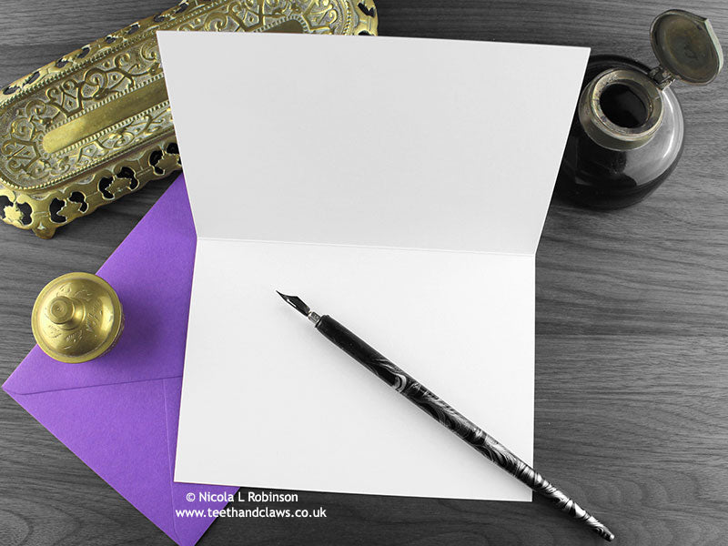 Owls birthday card, shown open and flat with blank inside, on a purple envelope, alongside vintage Victorian pen and writing desk accessories. Design and illustration © Nicola L Robinson | Teeth and Claws