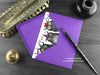 Owls birthday card, shown lying flat, with my original pen and ink illustration of owls, inside an open purple envelope. With vintage Victorian pen and writing desk accessories. Design and illustration © Nicola L Robinson | Teeth and Claws
