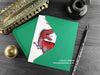 T rex greeting card, shown lying flat, with my original pen and ink illustration of a Tyrannosaurus Rex, inside an open green envelope. With vintage Victorian pen and writing desk accessories. Design and illustration © Nicola L Robinson | Teeth and Claws