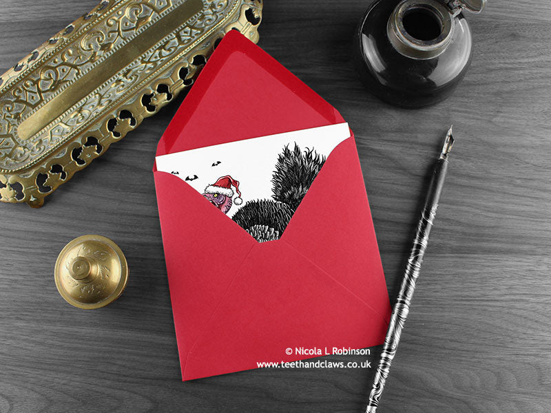 Gothic Turkey Christmas card, shown lying flat, with my original pen and ink illustration of a turkey, inside an open red envelope. With vintage Victorian pen and writing desk accessories. Design and illustration © Nicola L Robinson | Teeth and Claws
