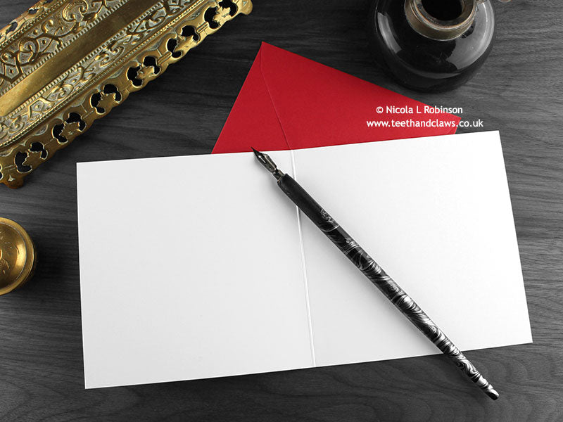 Gothic Turkey Christmas card, shown open and flat with blank inside, on a red envelope, alongside vintage Victorian pen and writing desk accessories. Design and illustration © Nicola L Robinson | Teeth and Claws