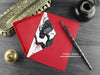 Owls love card, shown lying flat, with my original pen and ink illustration of two Gothic owls, inside an open red envelope. With vintage Victorian pen and writing desk accessories. Design and illustration © Nicola L Robinson | Teeth and Claws