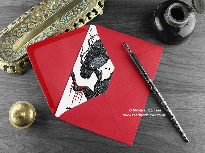 Owls love card, shown lying flat, with my original pen and ink illustration of two Gothic owls, inside an open red envelope. With vintage Victorian pen and writing desk accessories. Design and illustration © Nicola L Robinson | Teeth and Claws