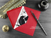 Gothic Ravens love card, shown lying flat, with my original pen and ink illustration of two ravens, inside an open red envelope. With vintage Victorian pen and writing desk accessories. Design and illustration © Nicola L Robinson | Teeth and Claws