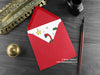 Dinosaur Christmas card, shown lying flat, with my original pen and ink illustration of festive diplodocus, inside an open red envelope. With vintage Victorian pen and writing desk accessories. Design and illustration © Nicola L Robinson | Teeth and Claws