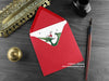 Pteranodon Christmas card, shown lying flat, with my original pen and ink illustration of a festive pteranodon, inside an open red envelope. With vintage Victorian pen and writing desk accessories. Design and illustration © Nicola L Robinson | Teeth and Claws